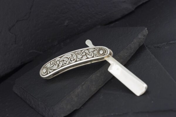 Antique straight razor with ornate silver handle.