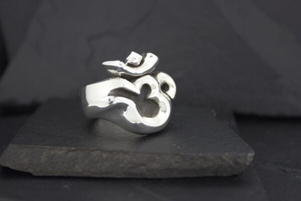 Silver ring featuring the Om symbol on a dark background.
