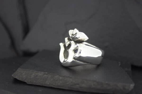 Silver ring featuring a hand and rose design.