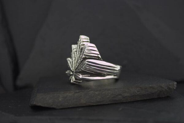 Art deco silver ring with geometric fan design on black background.