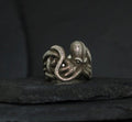 Intricately designed octopus ring on a dark surface.