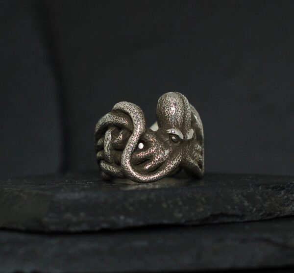 Intricately designed octopus ring on a dark surface.