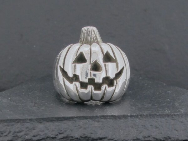 A small silver pumpkin with carved jack-o'-lantern face.