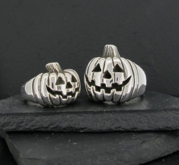 Two silver jack-o'-lantern pumpkin decorations on black stones.