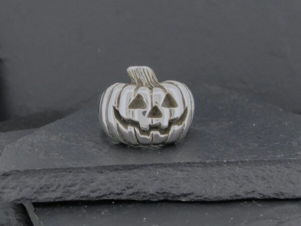 Silver pumpkin charm with a jack-o'-lantern face.