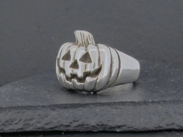 A silver ring featuring a carved jack-o'-lantern pumpkin design.