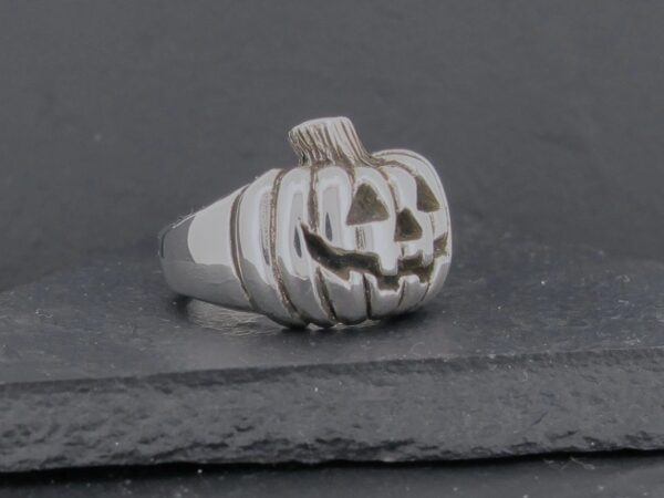 Silver ring shaped like a carved pumpkin with a smiling face.