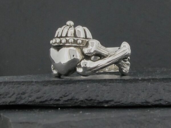 A silver charm shaped like a helmet and crossed bones.
