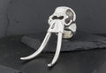 Silver skull ring with elongated tusks on a dark surface.