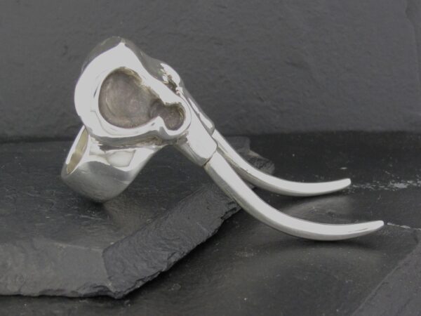 Close-up of a silver ring with a heart-shaped design and two curved extensions.
