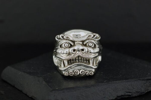 Intricately carved silver ring with a fierce mythical face design.