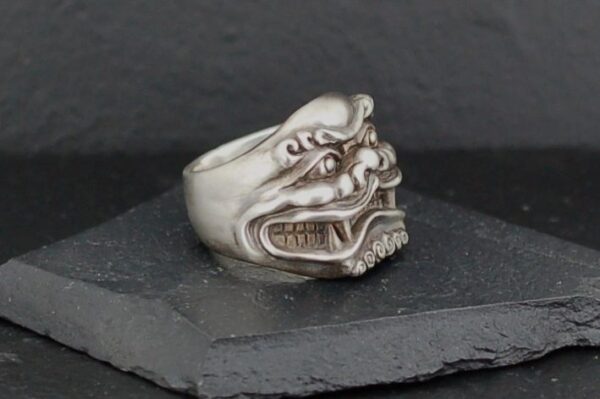 A silver ring featuring a detailed dragon face design.