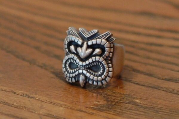 A silver ring with an intricate tribal design on a wooden surface.