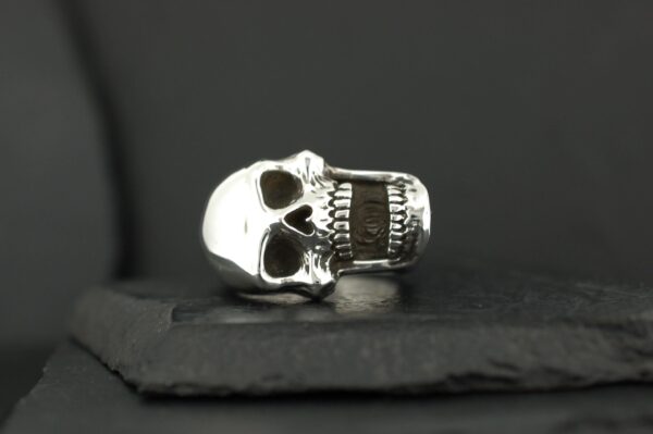 A silver skull ring with detailed teeth and hollow eyes.