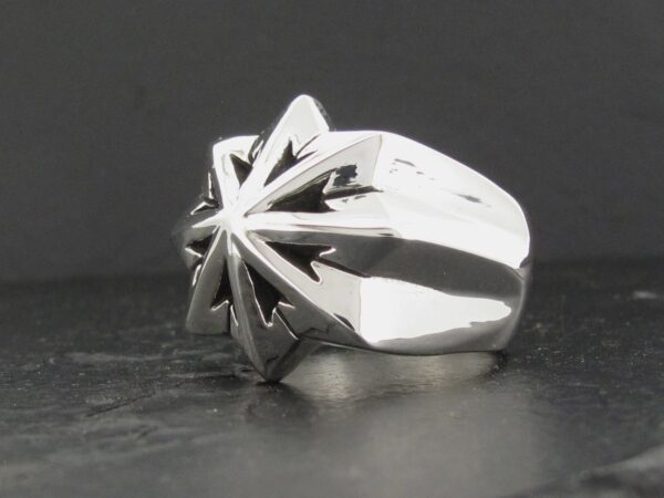 Polished silver ring with a starburst design on top.
