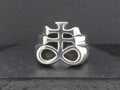 Silver ring with an intricate, symbolic design on a dark background.