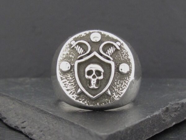 Silver ring featuring a skull emblem with a shield and snake design.
