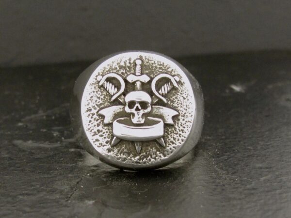 Silver ring with skull and crossed sickles emblem.