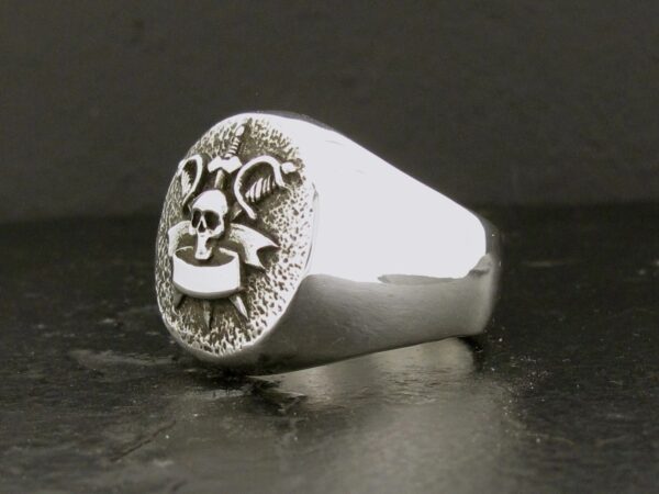 Silver ring with a carved face design on top.