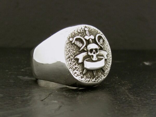 Silver ring with a playful face engraving on a textured background.
