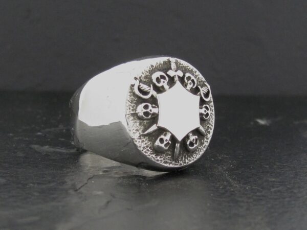 A silver ring with skulls encircling a star.