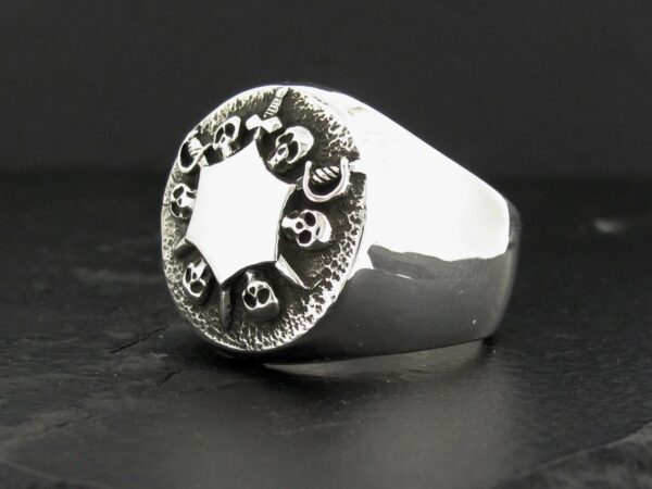 Silver ring with skull design around a star-shaped center.