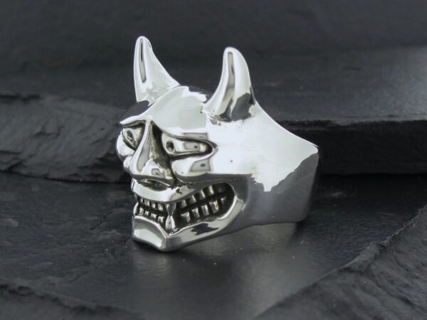 A white ceramic mask resembling a traditional Japanese oni demon.