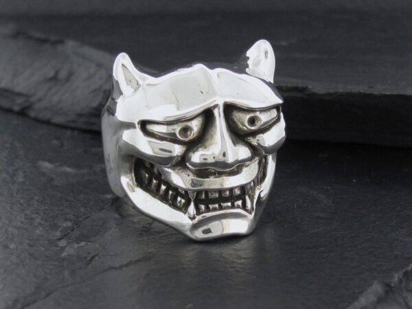 Silver ring shaped like a menacing demon mask with detailed facial features.