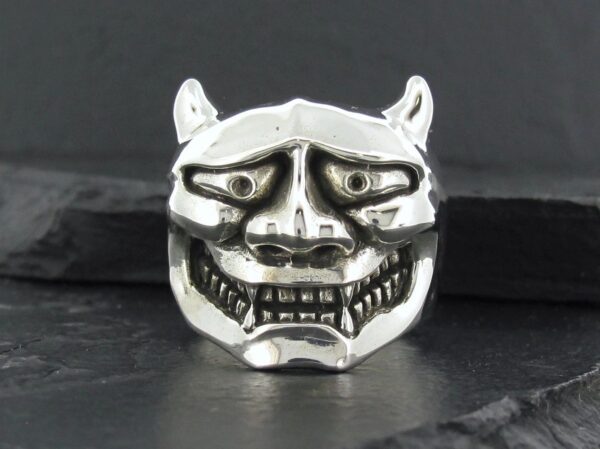 Silver demon mask ring with intricate facial details.
