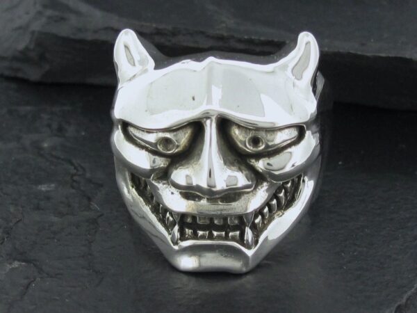 A metallic mask with a devilish, grinning face and horns.