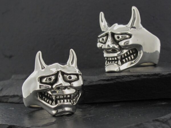 Two silver rings shaped like menacing demon faces with horns.