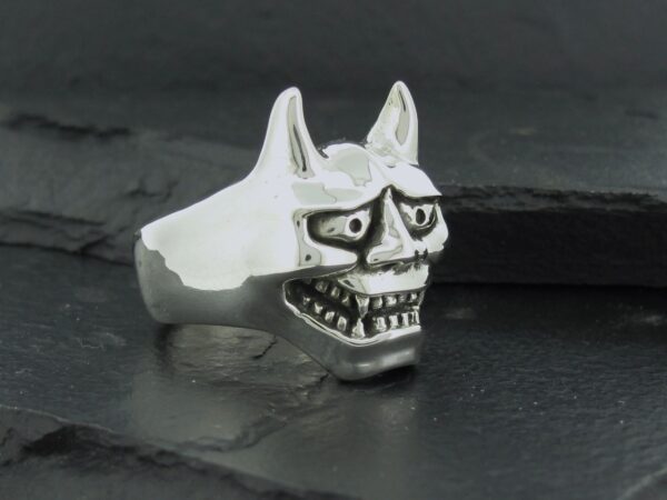 A silver ring featuring a detailed skull with sharp teeth and pointed ears.