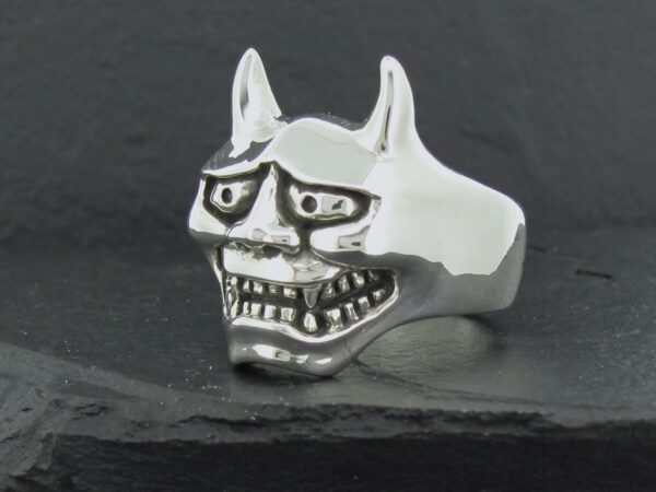 Silver ring shaped like a fierce demon mask with sharp teeth and horns.