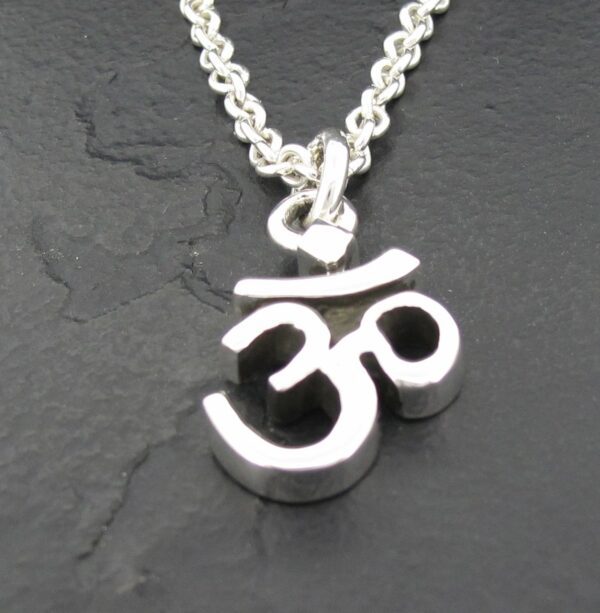 Silver Om symbol pendant on a chain against a dark background.