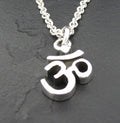 Silver Om symbol pendant on a chain against a dark background.
