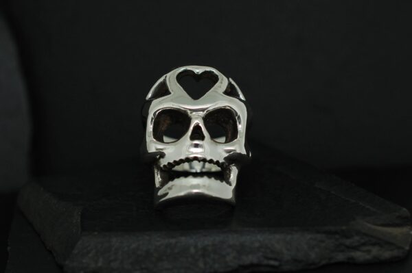 A decorative skull with heart-shaped eye sockets on a black background.