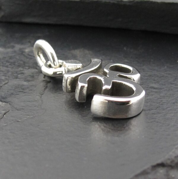 A silver pendant with the word 'this' on a dark surface.
