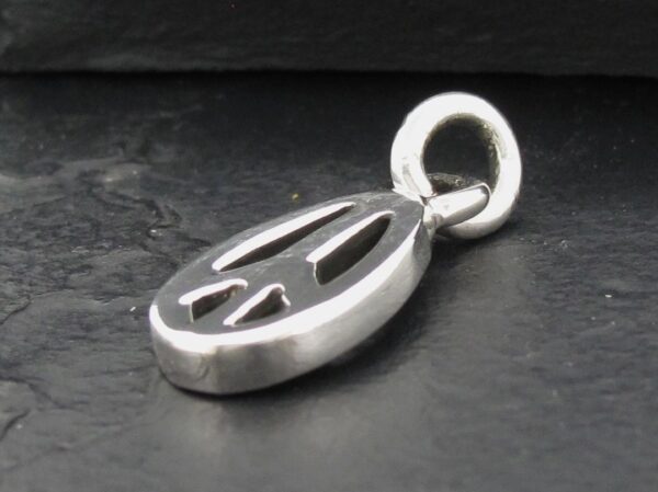 Close-up of a silver peace sign pendant on a dark surface.