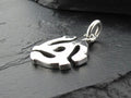 Close-up of a silver pendant with a unique abstract design on a dark surface.