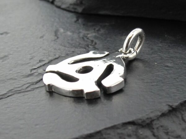 Close-up of a silver pendant with a unique abstract design on a dark surface.