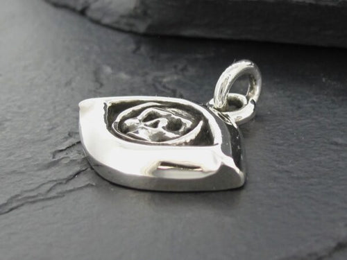 Close-up of a silver eye-shaped pendant on a dark surface.