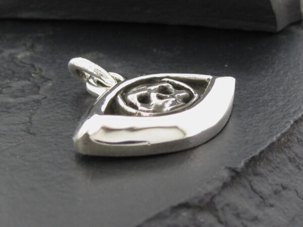 Close-up of a silver eye-shaped pendant with intricate detailing.