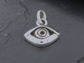 A silver eye-shaped pendant on a dark surface.