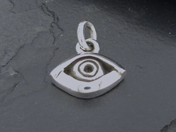 A silver eye-shaped pendant on a dark surface.