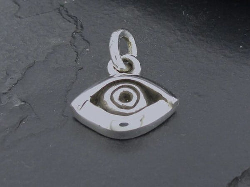 A silver eye-shaped pendant on a dark surface.