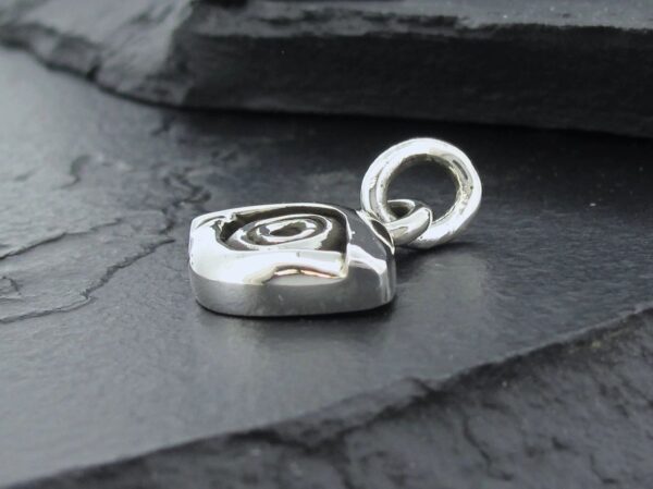 Close-up of a silver heart-shaped pendant on a dark surface.