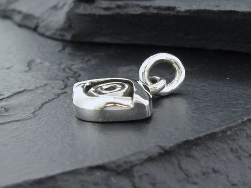 Close-up of a silver heart-shaped pendant on a dark surface.