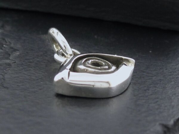 Close-up of a polished silver pendant with a swirl design.