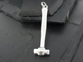 Small silver hammer pendant on a textured dark surface.