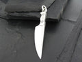 A silver knife pendant on a dark surface.